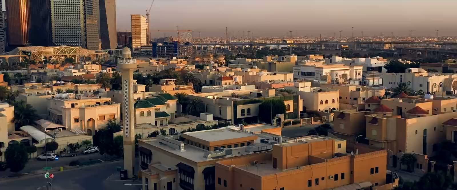 مشهد جوّي لمدينة الرياض عند الغروب — أحياء سكنية وأبراج مركز الملك عبدالله المالي